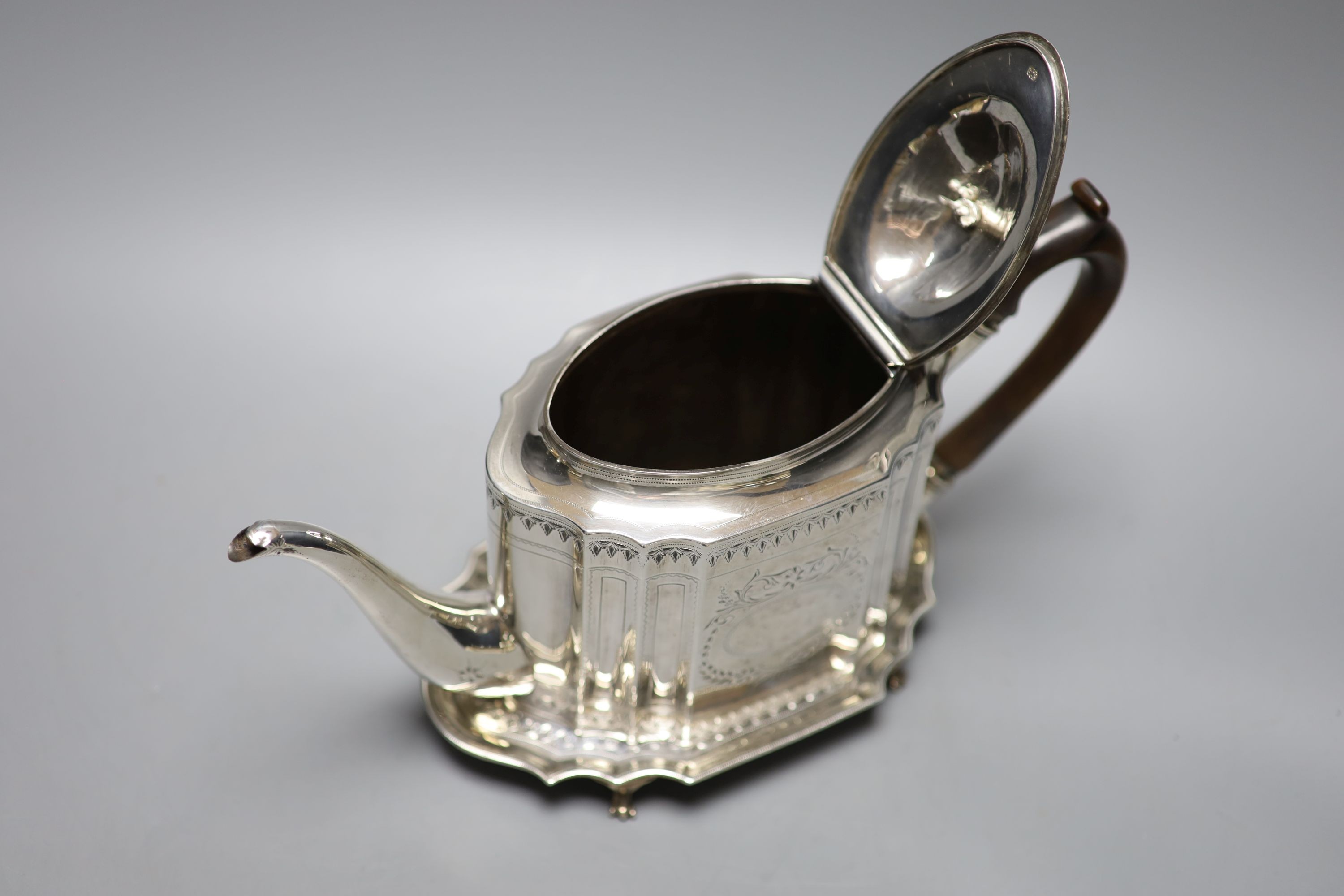 A George III bright cut engraved oval teapot and matching stand, Soloman Hougham, London, 1794, stand 19.3 cm, gross 20oz.